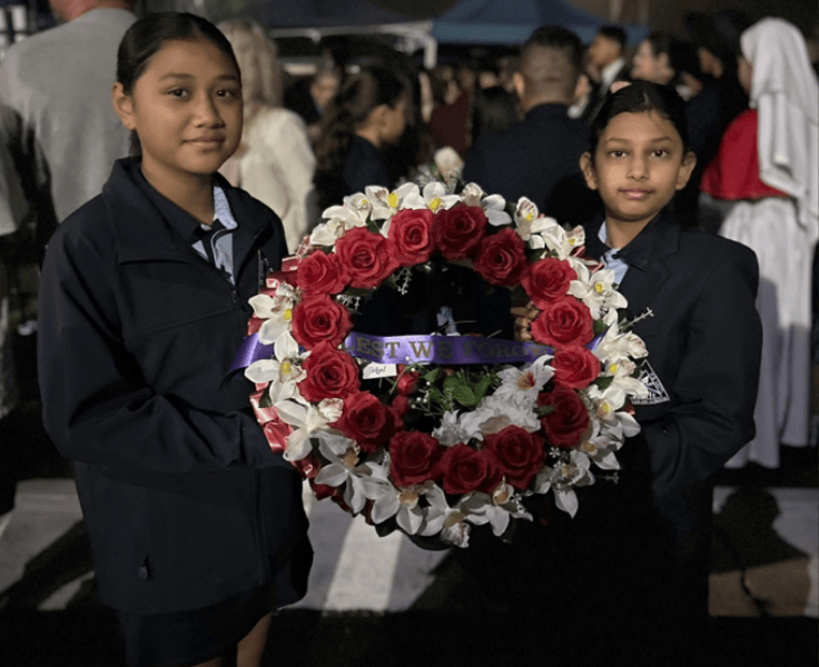Image of 2 student leaders at the dawn Anzac Day service holding a wreath.