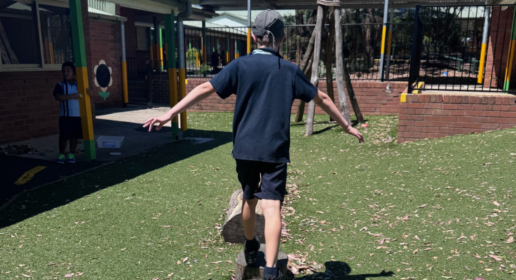 Student learning to balance and walk along a log.