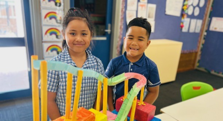 Two students view the support unit art project of a roller coaster.