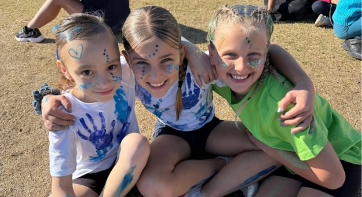 Three students posing for a photo at the athletics carnival. Dressed in house colours.