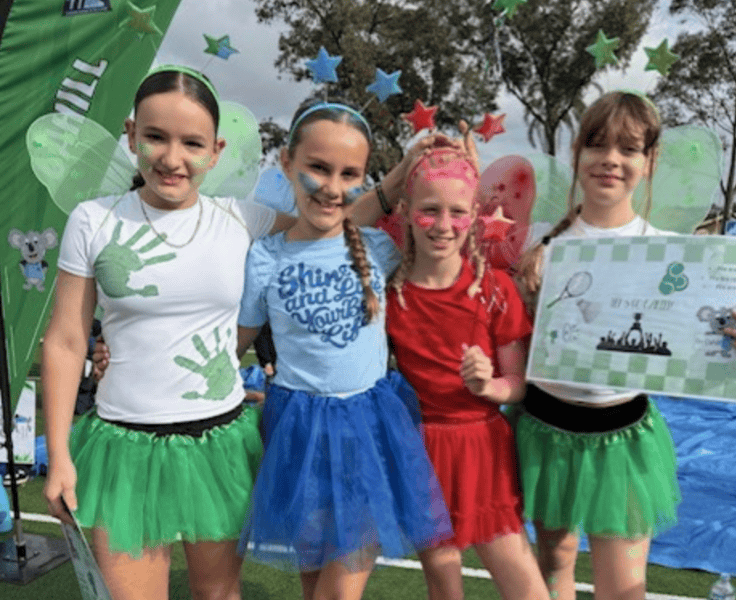 Four students showing their house costumes for the athletics carnival.